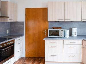 eine Küche mit weißen Schränken und einer Mikrowelle in der Unterkunft Apartment in Brilon with a small garden in Brilon