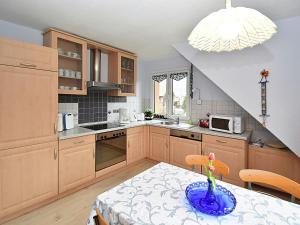 una cocina con armarios de madera y una mesa con un jarrón. en Holiday home in the Thuringian Forest en Seligenthal