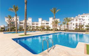 a swimming pool with palm trees and buildings at Gorgeous Apartment In Roldán With Wifi in Los Tomases