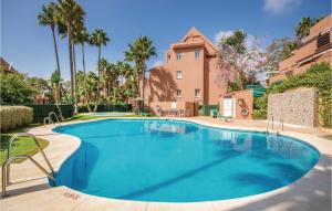 une grande piscine bordée de palmiers et un bâtiment dans l'établissement Cozy Apartment In Casares Costa With Kitchen, à Bahia de Casares