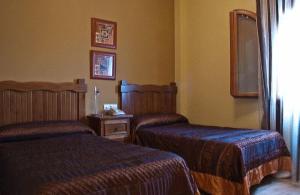 Habitación de hotel con 2 camas y mesa en Hotel Rural Miguel Angel, en Alcaracejos