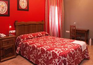 1 dormitorio con cama y pared roja en Hotel Rural Miguel Angel, en Alcaracejos