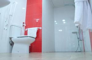 a bathroom with a toilet and a red wall at Hotel Rural Miguel Angel in Alcaracejos