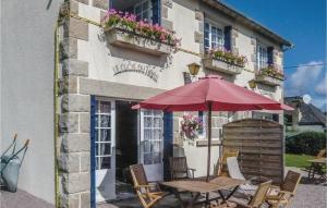a table with an umbrella in front of a building at Two-Bedroom Holiday Home In Saint Cast Le Guildo in LʼIsle-Saint-Cast