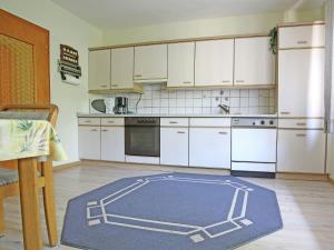 a kitchen with white cabinets and a blue rug on the floor at Secluded Apartment in Medebach with Terrace in Medebach