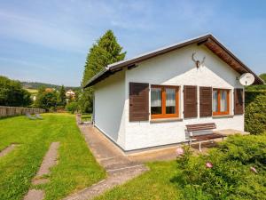 une petite maison blanche avec un banc dans une cour dans l'établissement Holiday home in Thuringia with garden, à Mosbach