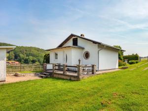 uma pequena casa branca com uma cerca de madeira em Holiday home in Thuringia with garden em Mosbach