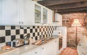 eine Küche mit weißen Schränken und einer Ziegelwand in der Unterkunft Amazing Home In Guern With Wifi in Guern