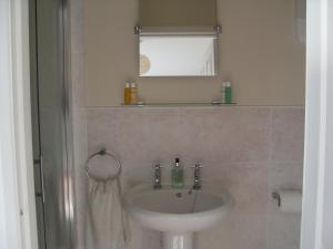 a bathroom with a sink, mirror and bath tub at Dol aur Bed and Breakfast in Harlech