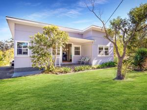 a white house with a lawn in front of it at Sirocco Cottage - pet-friendly Huskisson home in Huskisson