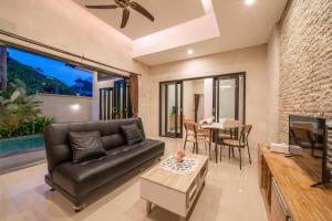 Una sala de estar con un sofá de cuero y una mesa. en Viros Luxury Villa 2BR Private Pool, en Jimbaran