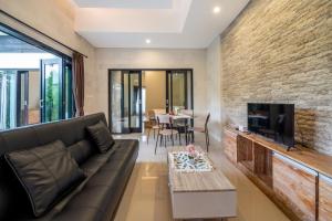 Una sala de estar con un sofá y un televisor. en Viros Luxury Villa 2BR Private Pool, en Jimbaran