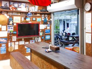 a room with a tv on a wall with a table at Sesoko Island Guest House Kafuu Village in Motobu