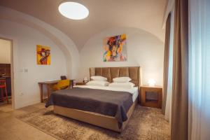 a bedroom with a bed and a table with a chair at Apartman Boutique Tvrđa in Osijek +3 photos