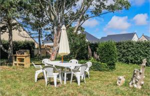 a table with a umbrella and chairs in a yard at Holiday Home Rue De Seychelles in Pirou