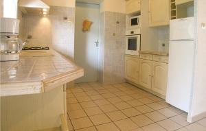 a kitchen with a white refrigerator and a tile floor at Amazing Home In La Tranche Sur Mer With Kitchen in La Tranche-sur-Mer