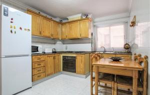 kuchnia z białą lodówką i drewnianym stołem w obiekcie 2 Bedroom Cozy Apartment In Santa Pola w mieście Santa Pola