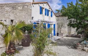 ein Steinhaus mit blauen Fenstern und einer Palme in der Unterkunft Stunning Home In Fontenille St,martin With Kitchenette in Fontenille-Saint-Martin-d'Entraigues