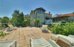 a patio with white chairs and a building at 2 Bedroom Stunning Home In Kastel in Kaštel