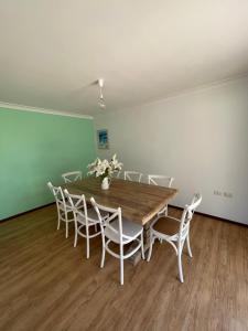 Siroque Busselton في بوسيلتون: غرفة طعام مع طاولة خشبية وكراسي بيضاء