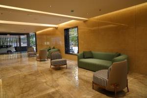 a lobby with a green couch and chairs at The Kings Park Grand-Near US Consulate in Chennai