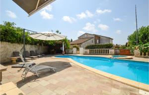 een zwembad met stoelen en een parasol bij Lovely Home In Aleria With Outdoor Swimming Pool in Aléria