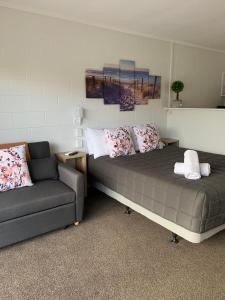 a bed and a couch in a room at Racecourse Motel in Paeroa