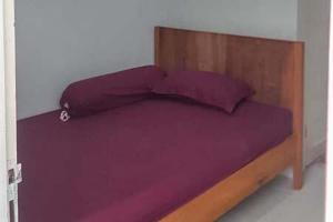1 cama con sábanas moradas y cabecero de madera en Kai Homestay Near Anyer Beach RedPartner, en Kareo