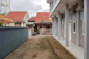 an empty alley between two buildings with red roofs at Kai Homestay Near Anyer Beach RedPartner in Kareo +5 photos