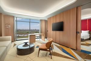 a living room with a couch and a bed and a television at La Quinta by Wyndham Weifang South in Weifang