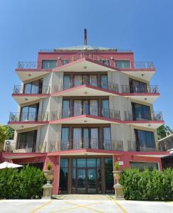 un edificio alto de color rosa con balcones. en Ellinis Hotel, en Varna