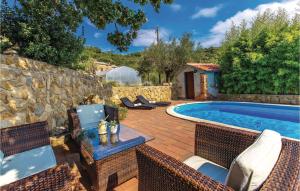 a patio with a swimming pool and chairs next to a stone wall at 2 Bedroom Cozy Apartment In Supetarska Draga in Supetarska Draga