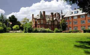 un grand bâtiment en briques avec une pelouse verte devant lui dans l'établissement Best Western Abbots Barton Hotel, à Canterbury