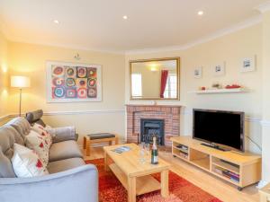 een woonkamer met een bank, een tv en een open haard bij Hops House in Weymouth