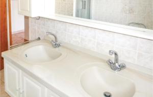 a bathroom sink with two faucets and a mirror at Beautiful Home In La Faute Sur Mer in La Faute-sur-Mer +3 photos
