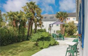 a patio with a table and chairs and palm trees at Holiday Home Rue De Kroas Prenn in La Forêt-Fouesnant