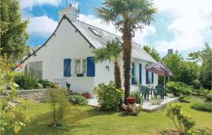a white house with a palm tree in the yard at Holiday Home Rue De Kroas Prenn in La Forêt-Fouesnant