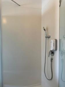 a shower in a bathroom with a phone on the wall at Cordia Hotel Surabaya Airport - Hotel Dalam Bandara - Formerly Ibis Budget Surabaya Airport in Sidoarjo