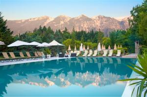 a swimming pool with chairs and mountains in the background at Residence Delle Rose in Tremosine Sul Garda