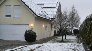 a house with snow on the ground next to a garage at Gästezimmer Carmen in Schwendi