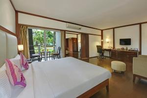 a bedroom with a large bed and a living room at Royal Orchid Resort & Convention Centre, Yelahanka Bangalore in Bangalore
