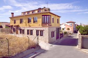 a large yellow house with a fence in front of it at Casa Rural El Mendrugo in Tornadizos de Ávila