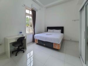 a bedroom with a bed and a desk and a window at RedDoorz Syariah at Jalan Godean in Ngabean