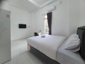a white bedroom with a bed and a television at RedDoorz Syariah at Jalan Godean in Ngabean