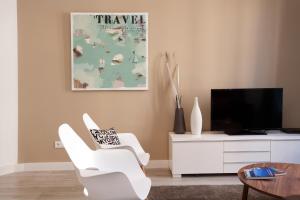 a living room with two white chairs and a tv at Click&Flat Seneca Suites in Barcelona