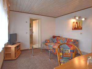 ein Wohnzimmer mit einem Sofa, einem Tisch und einem TV in der Unterkunft Charming bungalow with garden in Tabarz in Cabarz