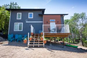 a tiny house with a deck and a porch at MANITOU BEACH COTTAGES by Prowess in Manitou Beach