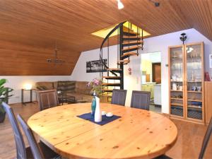 a wooden dining room table with chairs and a spiral staircase at Classy Holiday Home in Wolfshagen with Fenced Garden in Hahnenklee-Bockswiese