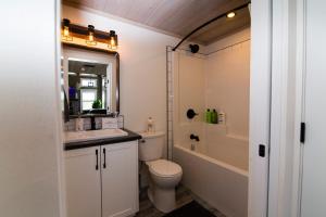 a bathroom with a toilet and a sink and a tub at MANITOU BEACH COTTAGES by Prowess in Manitou Beach +105 photos