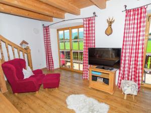 ein Wohnzimmer mit einem TV und einem roten Stuhl in der Unterkunft Quaint Holiday Home in Feldwies near Ski Area in Baumgarten